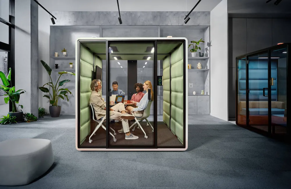 kantoor-inrichting-vergadercabine-hushfree-1000x650px2 Twee mannen die met twee vrouwen aan het vergaderen zijn in een witte HushFreeM vergadercabine van Mikomax met een groen interieur